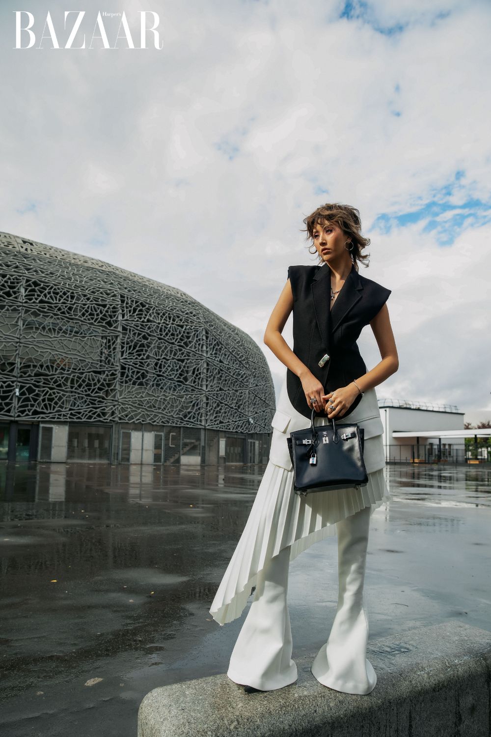 Nàng fashionista trong thiết kế áo blazer, phối pant-skirt xếp ly với chi tiết đánh cong, kết hợp hai tông màu nâu tro và trắng tại Paris Fashion Week.